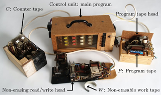 <p>Hasenjaeger&rsquo;s universal electromechanical Turing machine. The wiring in the control unit encodes a universal program, that uses only four states and two symbols, for simulating Wang B machines. The program of a Wang B machine may be stored on the program tape. There are two additional tapes which are used for the simulation, a counter tape and a work tape.</p>
<p>Source:<br /><a href="https://www.semanticscholar.org/paper/Wang's-B-machines-are-efficiently-universal%2C-as-is-Neary-Woods/72cf316d3954356650c14346da595ee25cbd169c" target="_blank">www.semanticscholar.org</a></p>